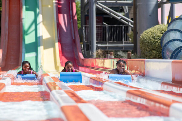 Cyclone Racers family of three racing on the splash zone. Feature image for outdoor waterpark page for reference.