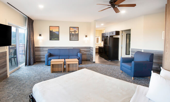 A spacious hotel suite with a living area, kitchenette, and bedroom.