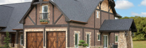 A large brick and stone building with a gray roof and wooden garage doors.