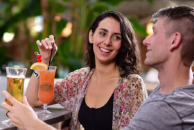 man and woman enjoying cocktails at a bar