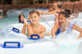 two kids splashing in a tube in the great wave, wave pool