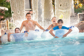 family going under the waterfall of the lazy river at lake wilderness outdoor park