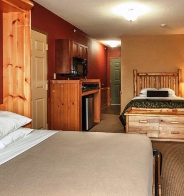 A hotel room with two beds, a kitchenette, and a TV.