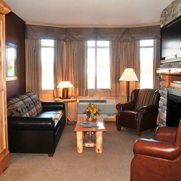 A hotel lobby with a sofa, armchairs, a coffee table, TV, and fireplace.