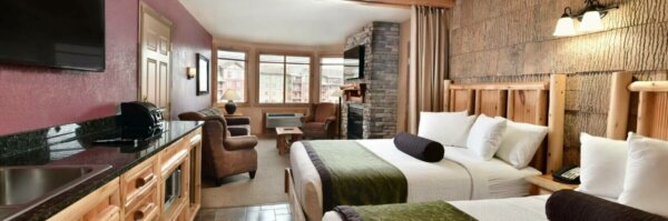 A wide view of a hotel suite with two beds, a sitting area, and a kitchenette.