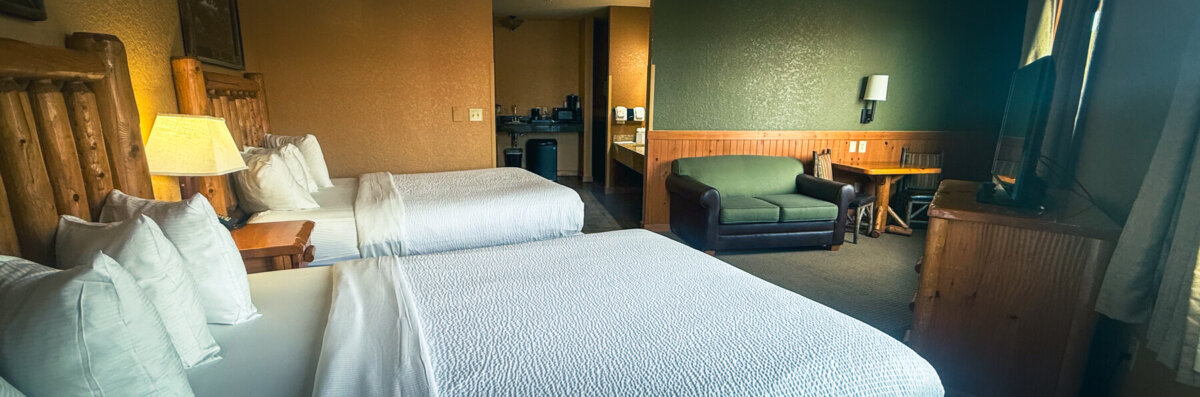 Family Suite banner image for room page. Shows two beds, a couch, a TV, and a kitchen area.