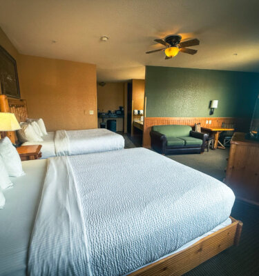 A hotel room with two beds, a sofa, and a TV.
