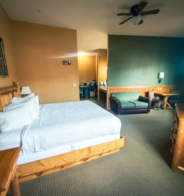 A hotel room with a large bed, desk, chair, and dresser.