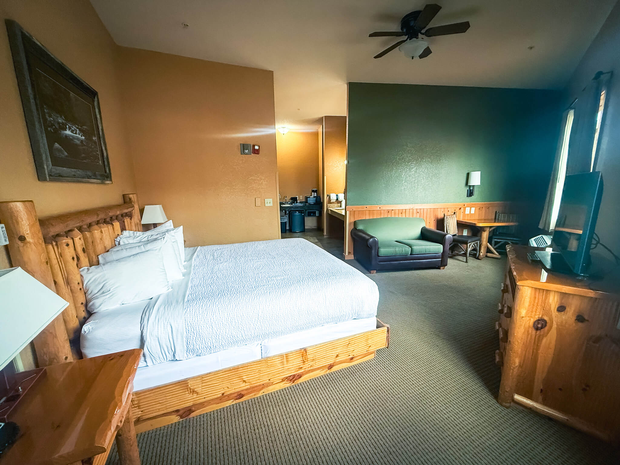 A wide-angle view of a hotel room with a large bed, sofa, and flat screen TV.