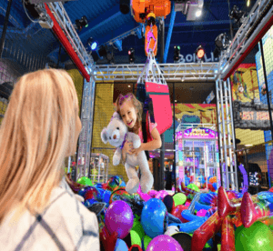 Human Crane feature image for Wilderness at the Smokies shows a girl hugging an item they picked up while lowered into a toy pit on a crane.